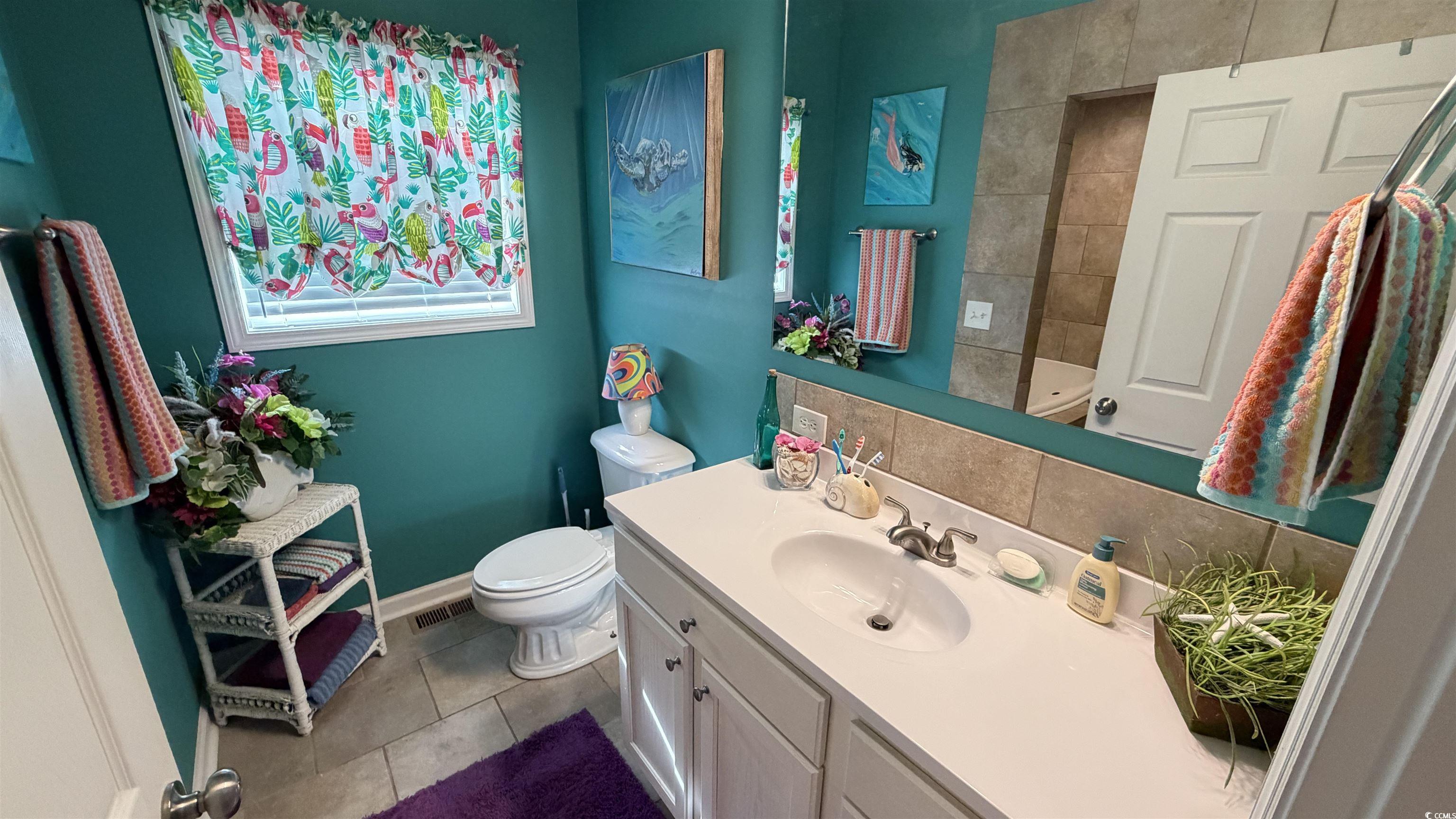 1517 Pisces Lane Myrtle Beach, SC 29575 - Photo 12 of 30 Bathroom featuring vanity, dark tile patterned floors, and decorative backsplash