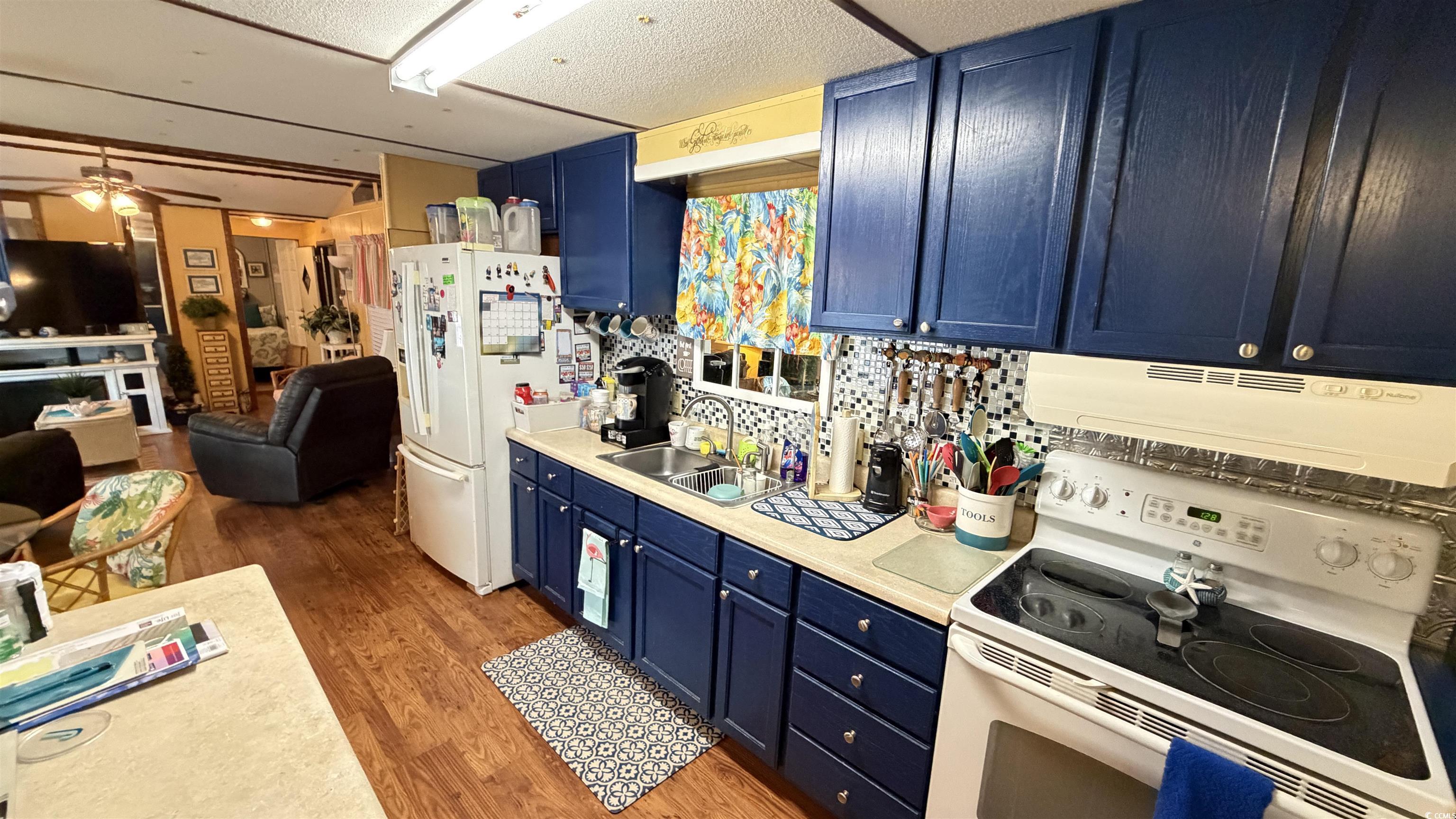 1517 Pisces Lane Myrtle Beach, SC 29575 - Photo 6 of 30 Kitchen featuring blue cabinetry, white appliances, light countertops, ventilation hood, and dark wood-style flooring