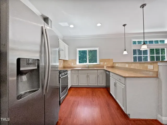 a kitchen with stainless steel appliances granite countertop a refrigerator a sink and wooden floors