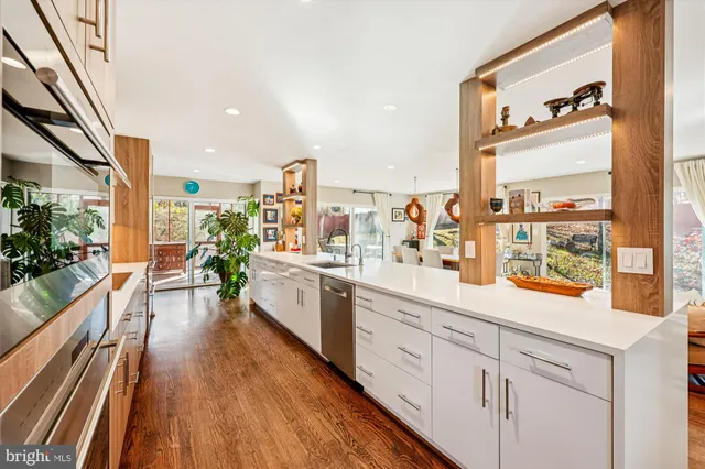 a large white kitchen with sink and wooden floor