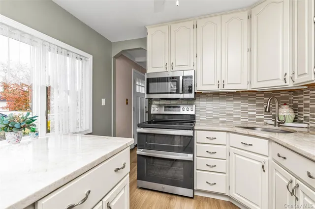 a kitchen with granite countertop white cabinets and stainless steel appliances