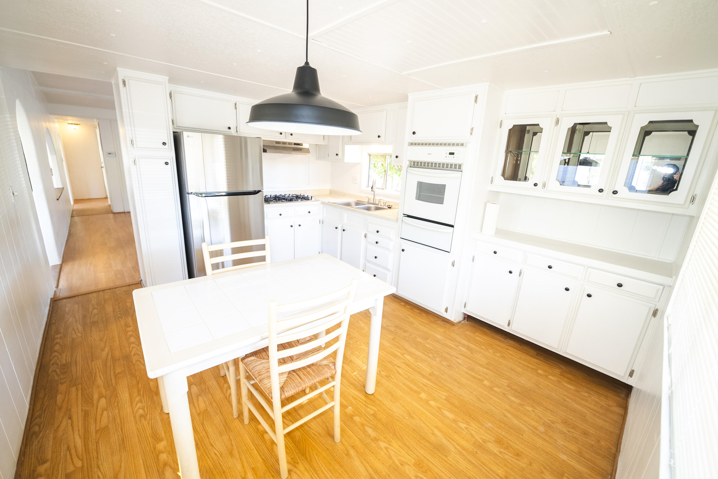 4025 State Street, Unit 26 Santa Barbara, CA 93110 - Photo 8 of 20 a kitchen with stainless steel appliances kitchen island granite countertop a refrigerator a stove a sink and white cabinets with wooden floor