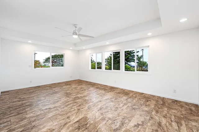 an empty room with windows and ceiling fan