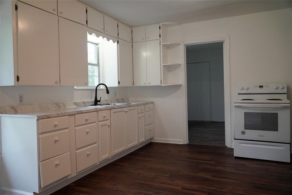 403 North Fairview Street Keene, TX 76059 - Photo 12 of 25 a kitchen with sink cabinets and wooden floor