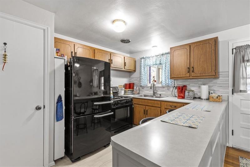 13733 Ormsby Drive Irwin, PA 15642 - Photo 7 of 24 a kitchen with stainless steel appliances granite countertop a refrigerator a sink dishwasher a stove and white countertops with wooden floor