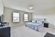 a spacious bedroom with a bed and a flat screen tv