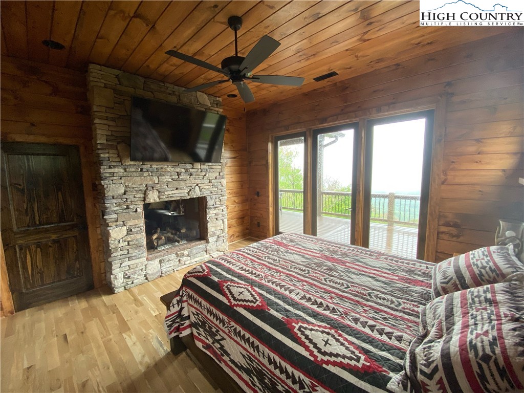 543 Broken Arrow Trail Boone, NC 28607 - Photo 27 of 35 a bedroom with a bed a fireplace and flat screen tv