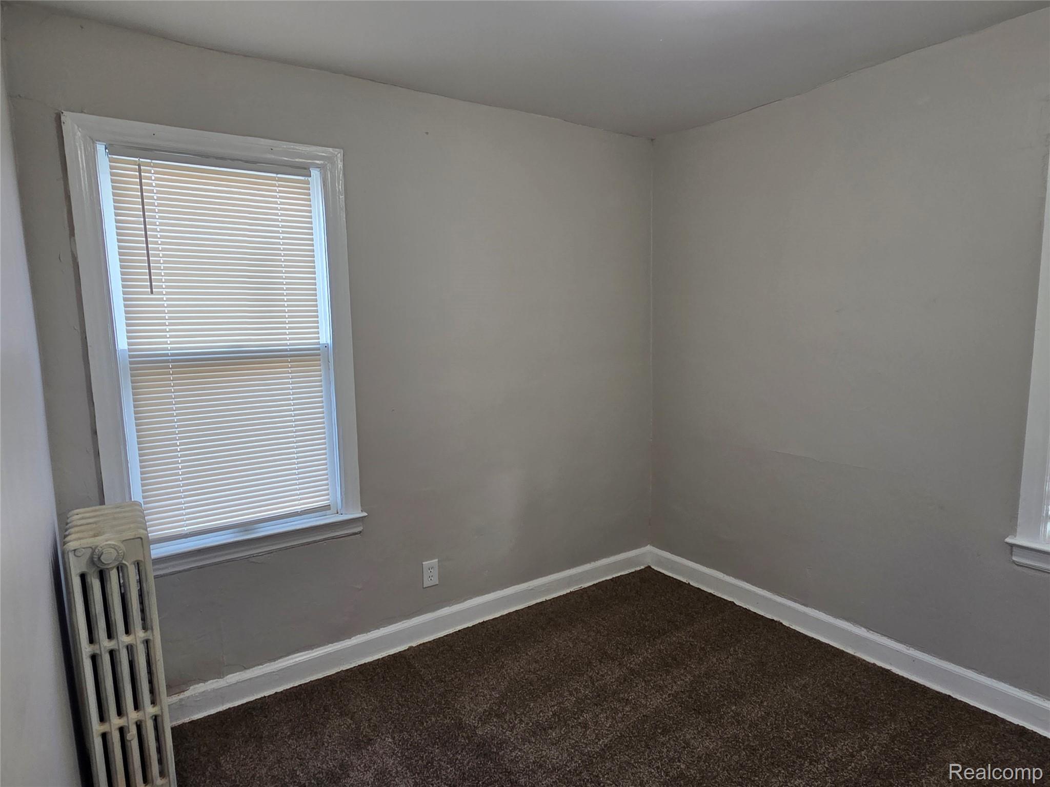5274 Nottingham Road Detroit, MI 48224 - Photo 7 of 18 Empty room featuring radiator heating unit and dark carpet