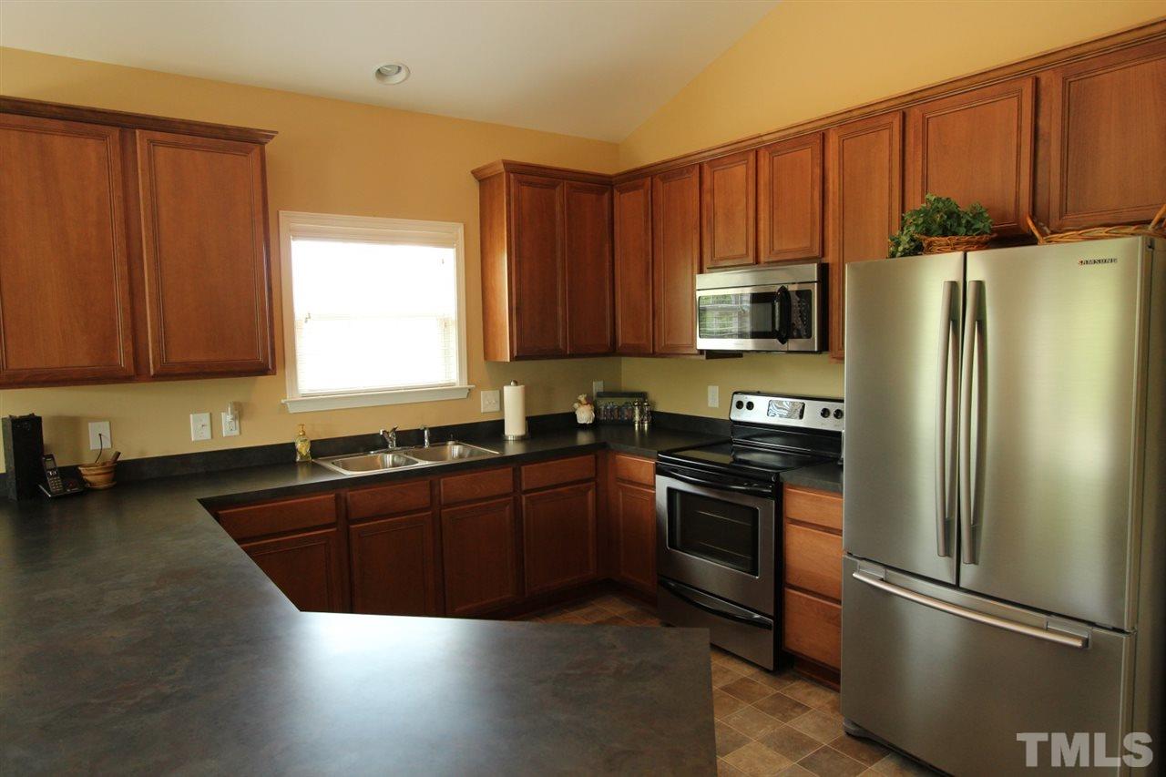 6312 Slopeside Court Raleigh, NC 27610 - Photo 4 of 22 a kitchen with wooden cabinets and stainless steel appliances