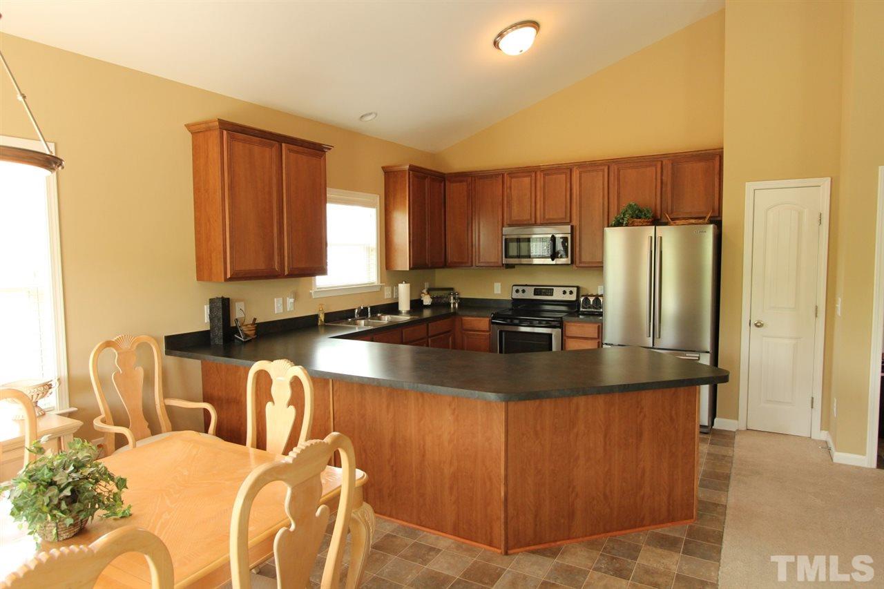 6312 Slopeside Court Raleigh, NC 27610 - Photo 8 of 22 a kitchen with stainless steel appliances granite countertop a refrigerator a stove a sink a counter space and cabinets