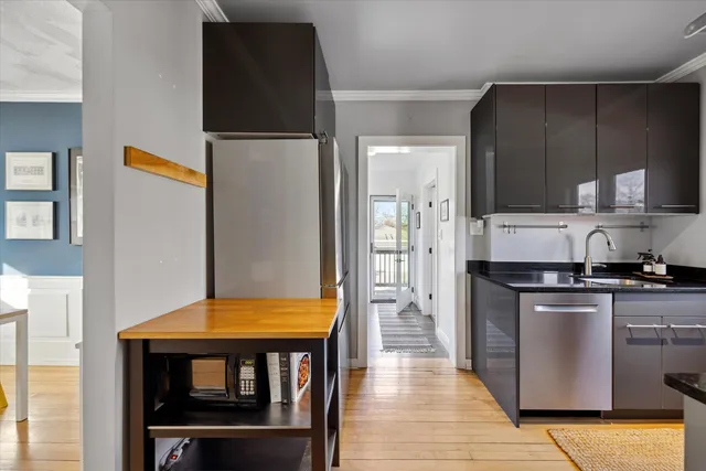 a kitchen with stainless steel appliances granite countertop a refrigerator a stove and a sink with wooden floor