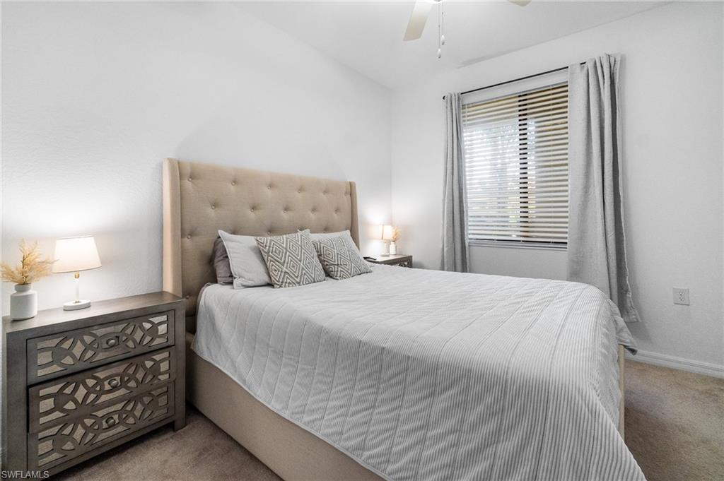 9596 Trevi Court, Unit 5413 Naples, FL 34113 - Photo 12 of 26 a bedroom with a bed a mirror and a lamp