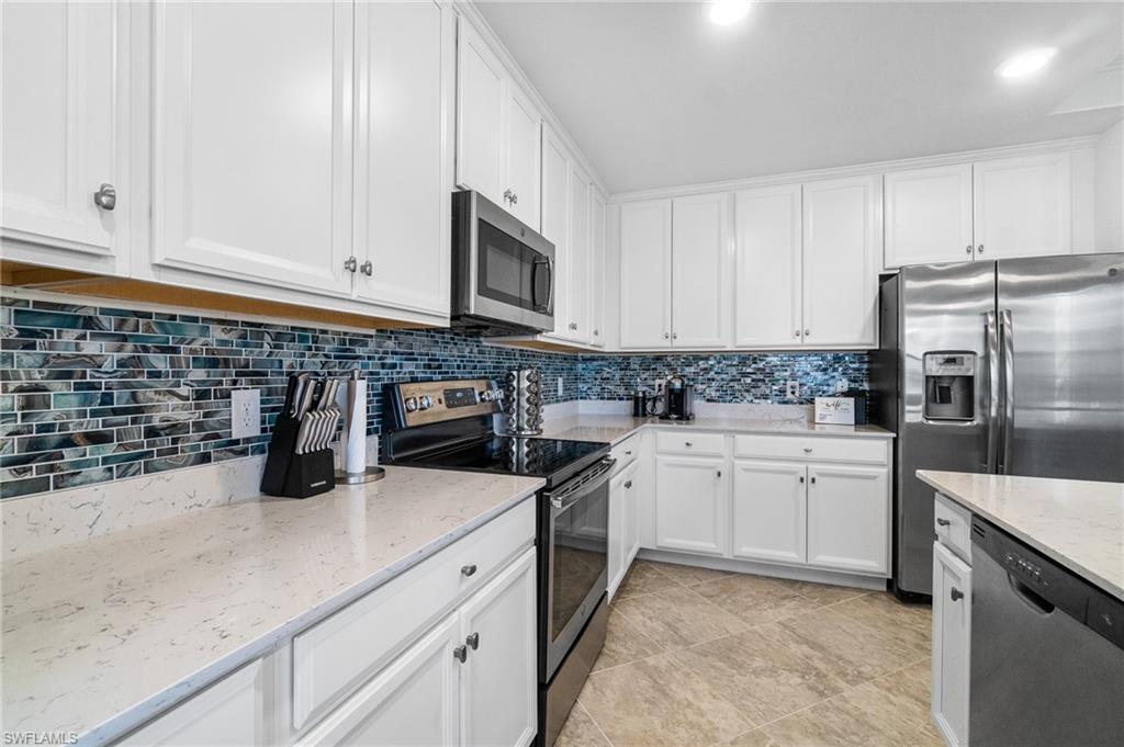 9596 Trevi Court, Unit 5413 Naples, FL 34113 - Photo 8 of 26 a kitchen with granite countertop white cabinets and stainless steel appliances