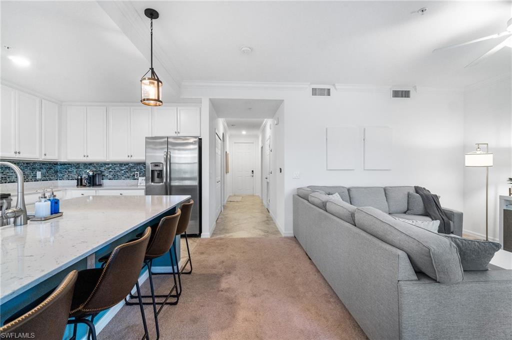 9596 Trevi Court, Unit 5413 Naples, FL 34113 - Photo 9 of 26 a living room with stainless steel appliances kitchen island furniture and a wooden floor