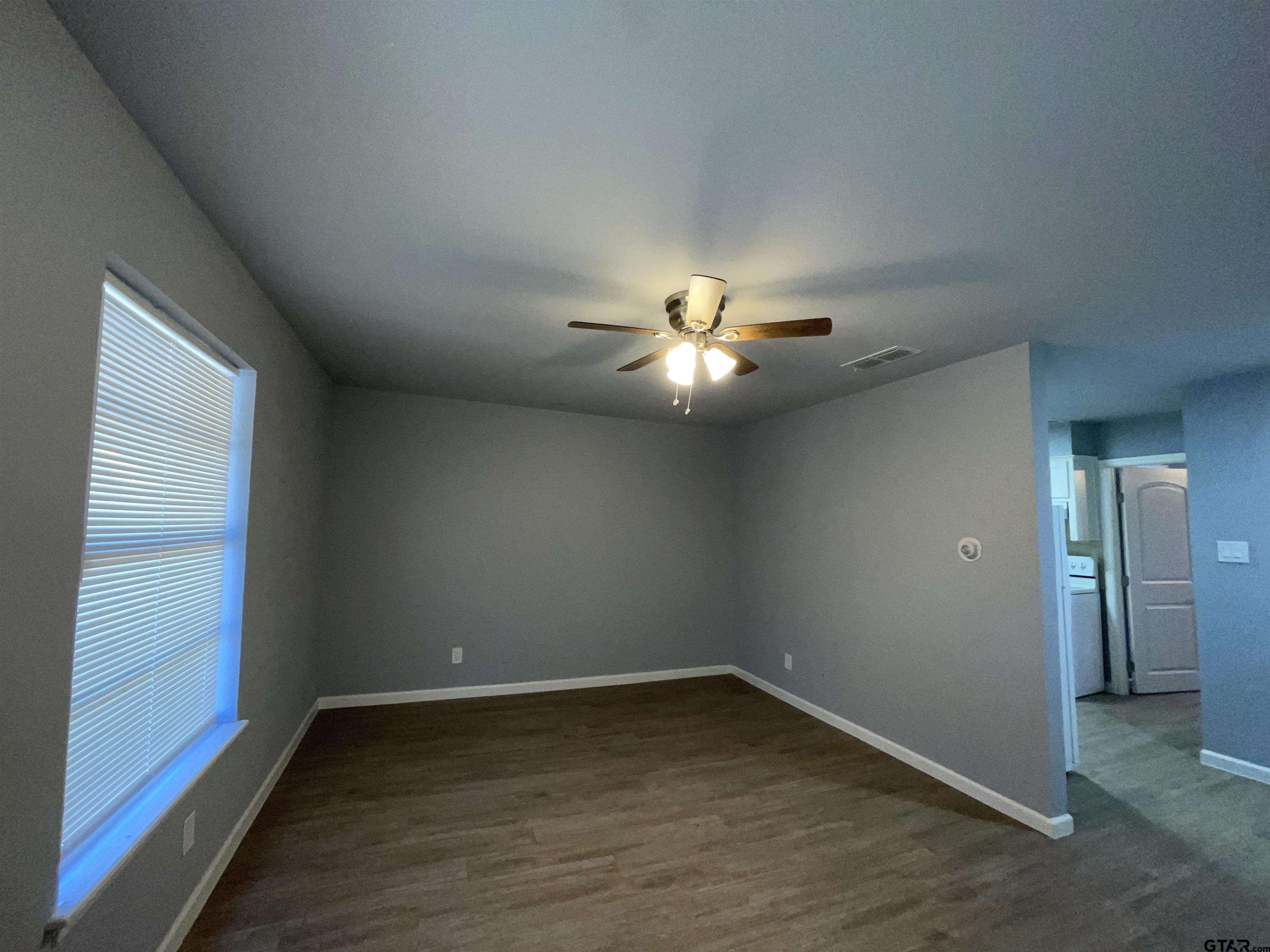 625 Augusta Avenue, Unit 10 Tyler, TX 75701 - Photo 2 of 9 an empty room with wooden floor fan and windows