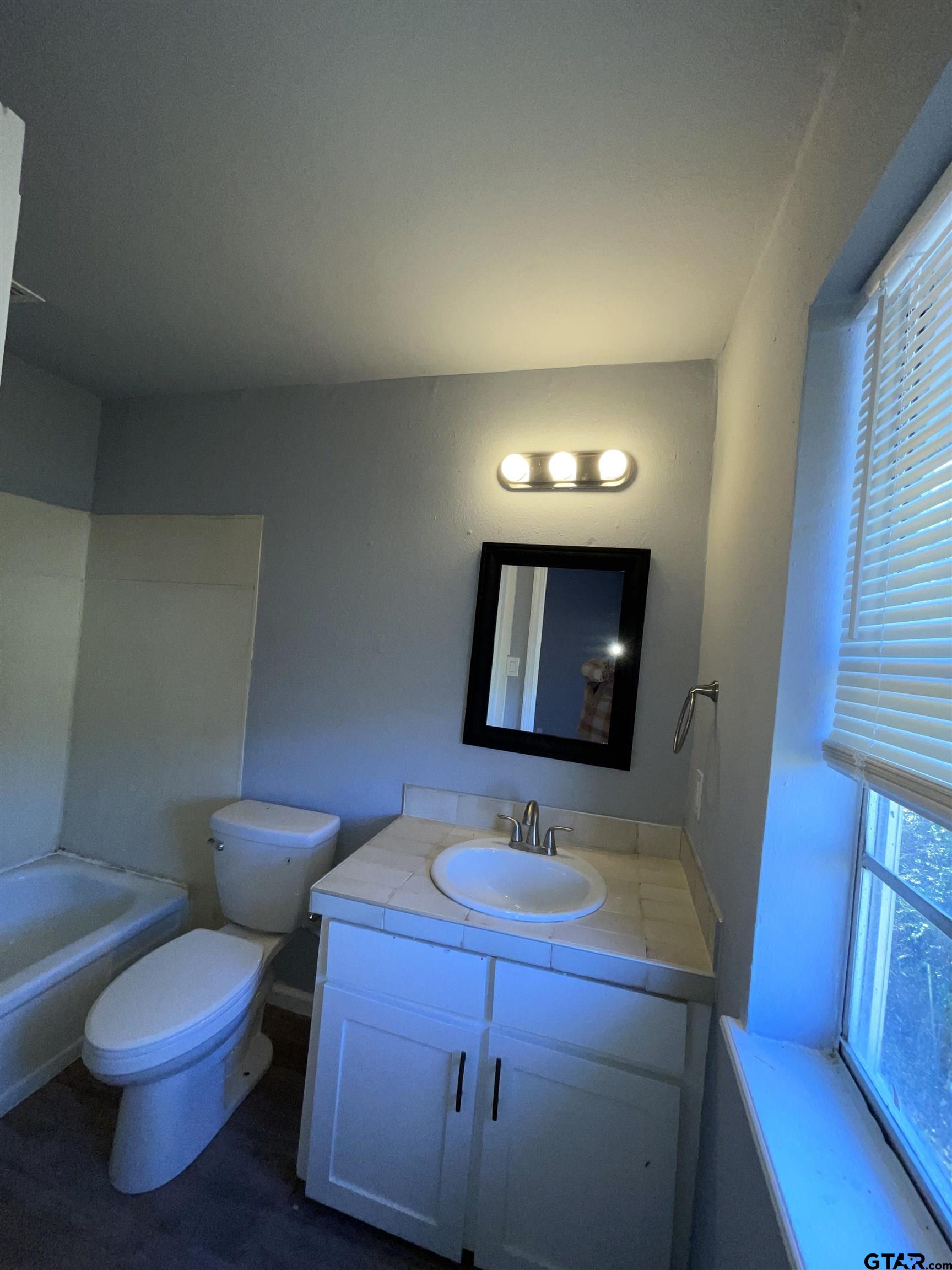 625 Augusta Avenue, Unit 10 Tyler, TX 75701 - Photo 9 of 9 a bathroom with a toilet sink and mirror