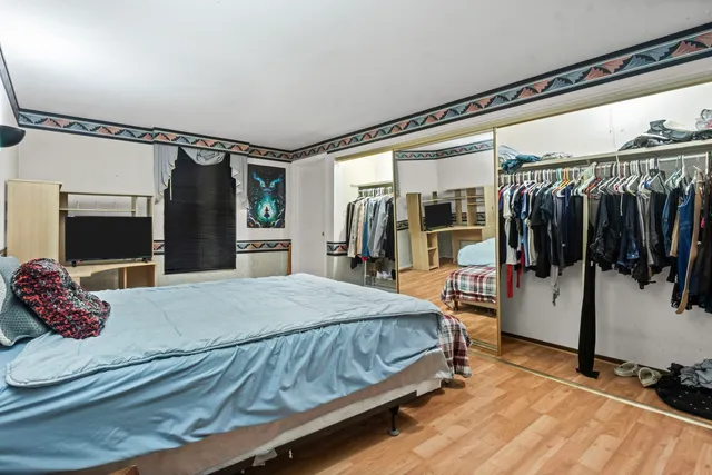 a bedroom with a bed and dresser with wooden floor