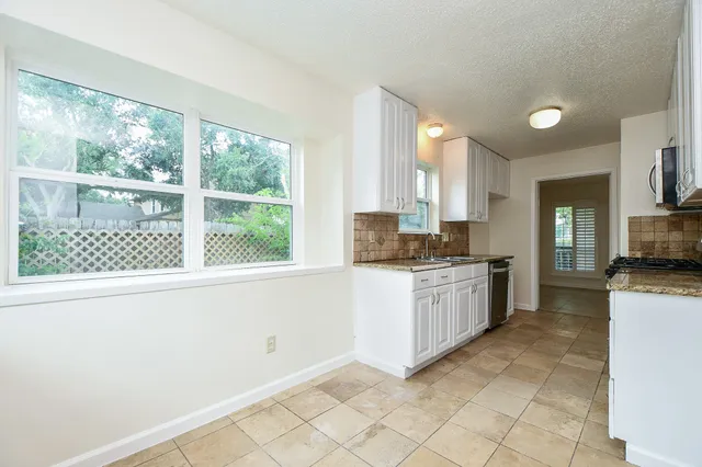 a kitchen with granite countertop a stove a sink and a refrigerator
