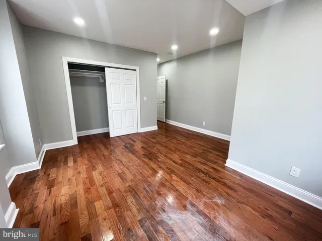 a view of an empty room with wooden floor and closet