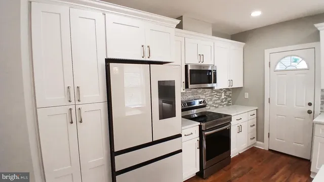 a kitchen with stainless steel appliances white cabinets and wooden floor