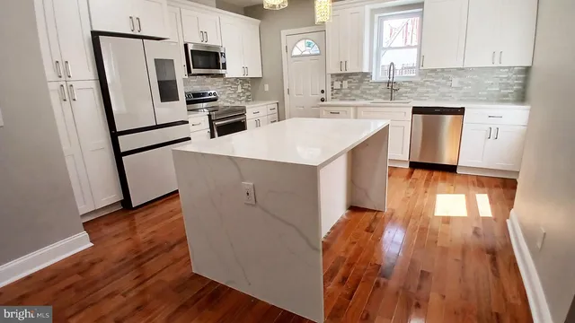 a kitchen with wooden floors white cabinets and stainless steel appliances