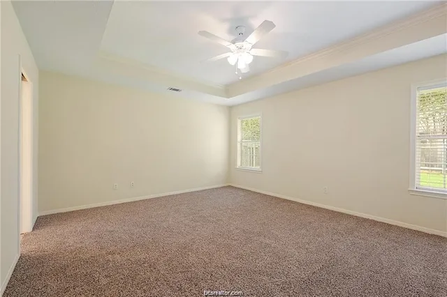 an empty room with windows and fan