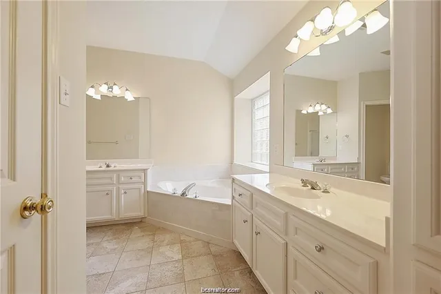 a spacious bathroom with a double vanity sink mirror and bathtub