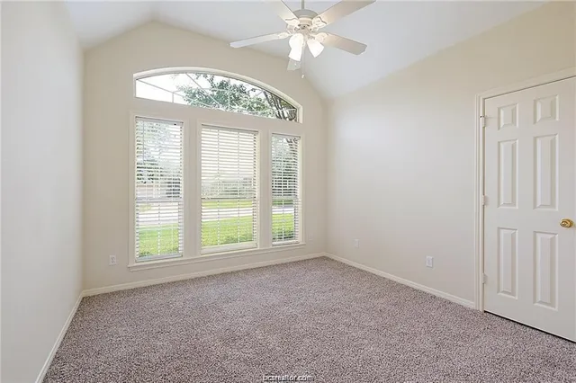 an empty room with a chandelier fan and windows