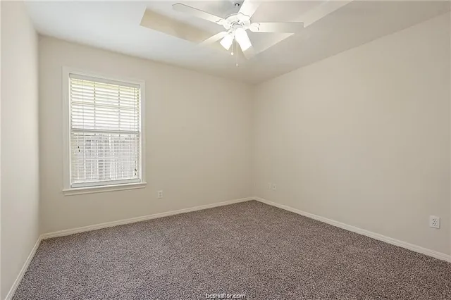 an empty room with a window and a fan
