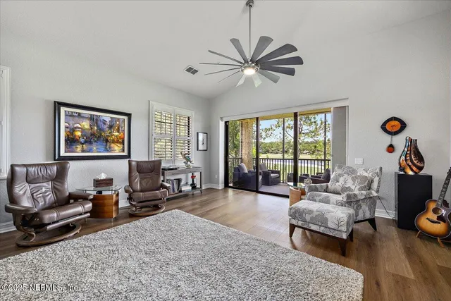 a living room with furniture floor to ceiling window and a flat screen tv