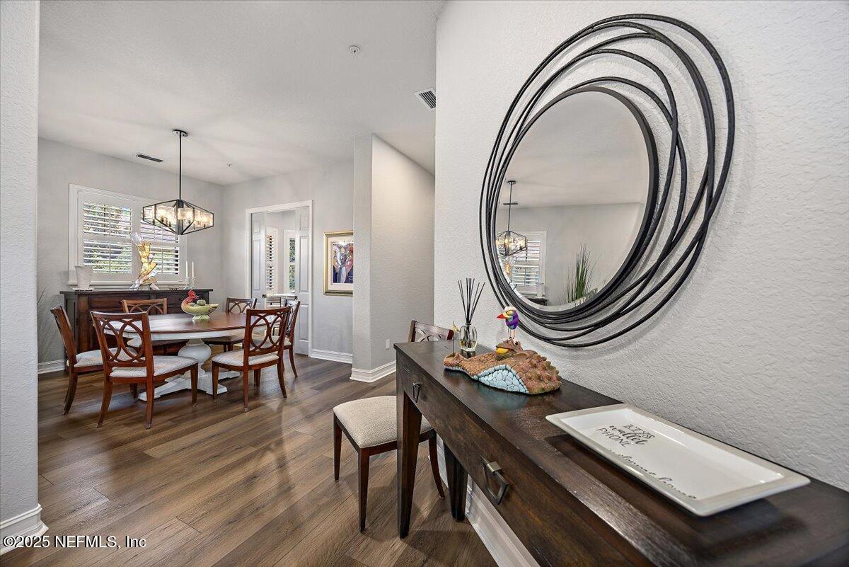 174 Laterra Links Circle, Unit 201 St. Augustine, FL 32092 - Photo 7 of 41 a dining room with wooden floor a chandelier a wooden table and chairs