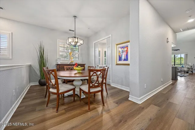 a dining room with furniture a chandelier and wooden floor