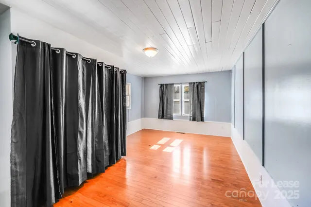a view of an empty room with window and wooden floor