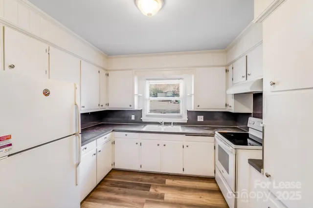 a kitchen with granite countertop a sink a stove and cabinets