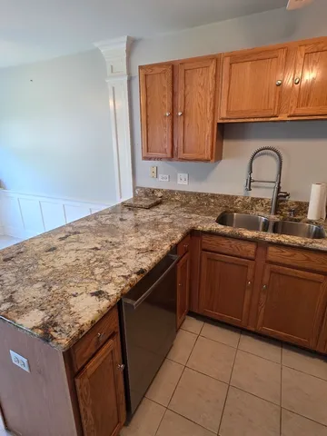 a kitchen with granite countertop a sink a stove top oven and cabinets