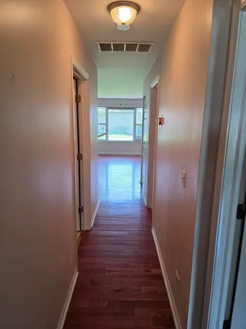 a view of a hallway with wooden floor and staircase
