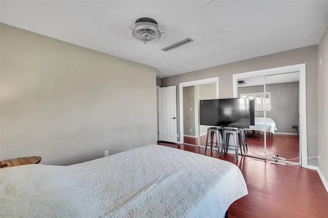 a view of a white house with a yard plants and large tree