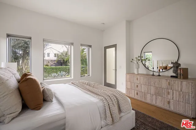 a bedroom with a bed a mirror and a large window