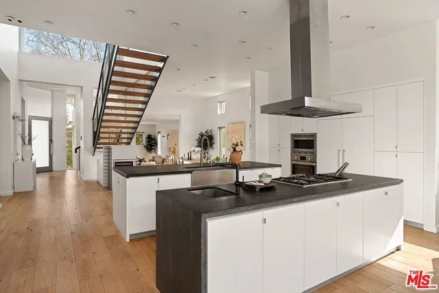 a kitchen with stainless steel appliances granite countertop a sink a stove and white cabinets