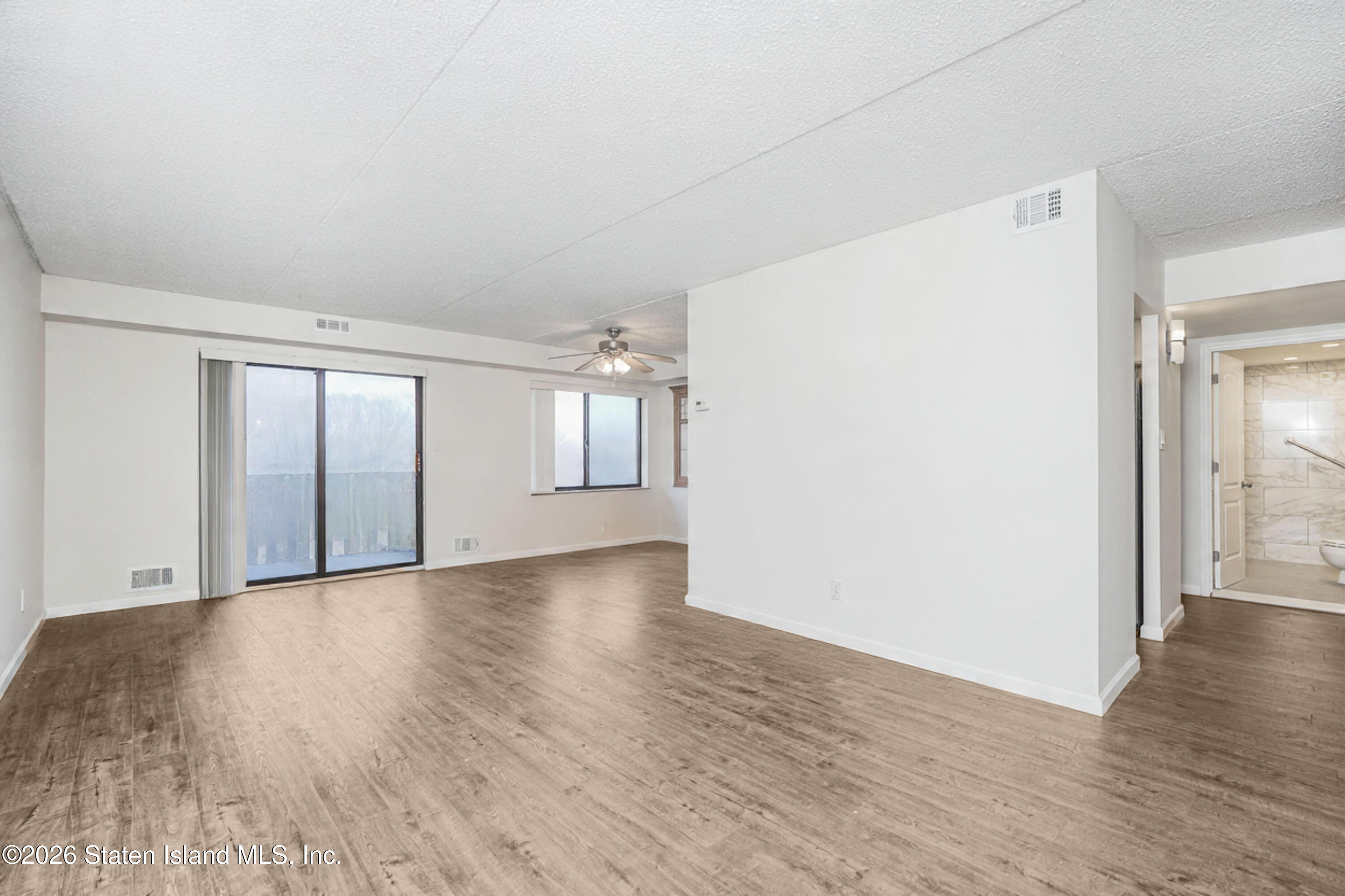 5 Windham Loop, Unit 6E Staten Island, NY 10314 - Photo 5 of 25 a view of an empty room with wooden floor and a window