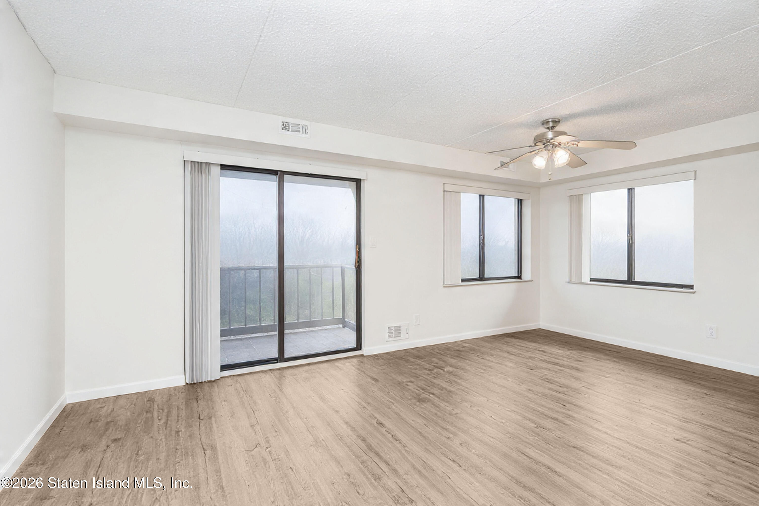 5 Windham Loop, Unit 6E Staten Island, NY 10314 - Photo 7 of 25 an empty room with wooden floor and windows