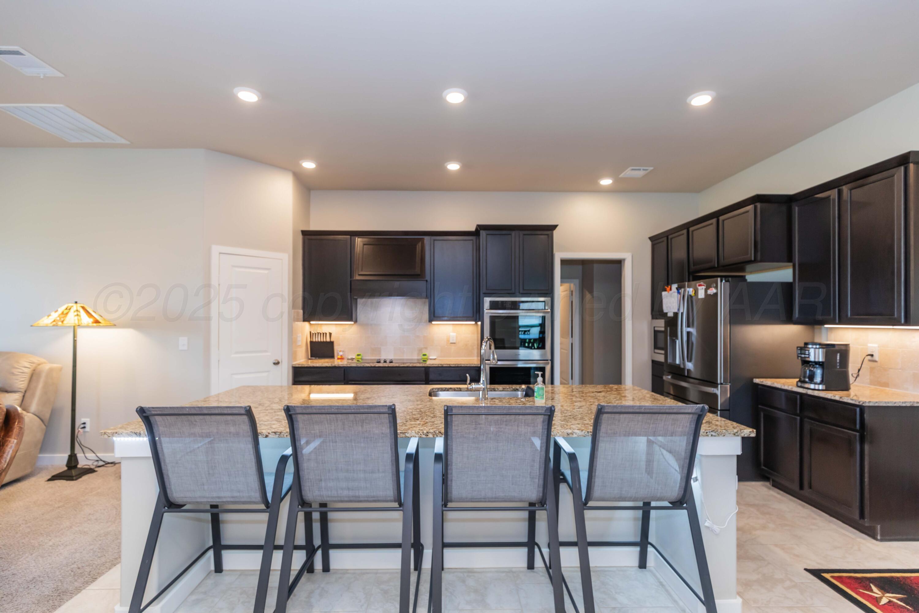 2600 Daybreak Lane Amarillo, TX 79124 - Photo 12 of 52 a kitchen with stainless steel appliances kitchen island granite countertop a dining table chairs refrigerator and microwave