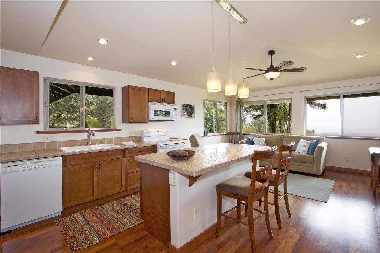 399 Omaopio Road, Unit B Kula, HI 96790 - Photo 4 of 30 a kitchen with a stove a sink a dining table and chairs with wooden floor