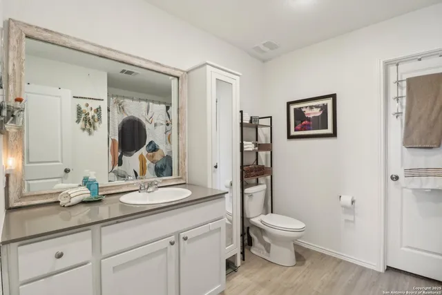 a bathroom with a granite countertop toilet a sink and a mirror