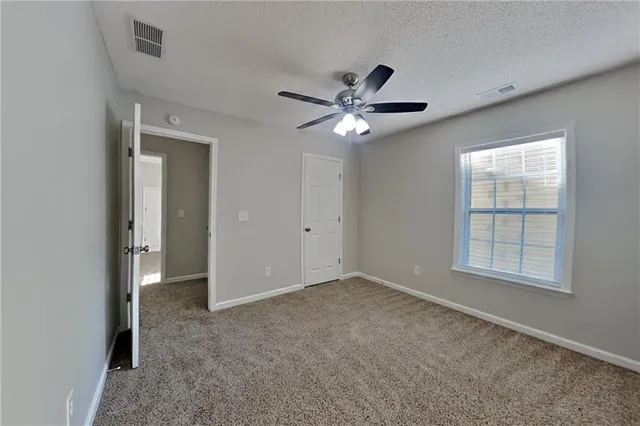 an empty room with chandelier fan and windows