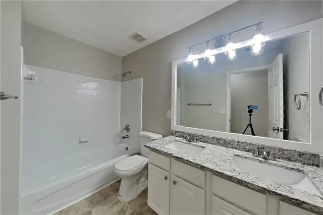 a bathroom with a granite countertop sink a toilet and a large mirror