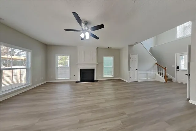 an empty room with wooden floor fan and windows