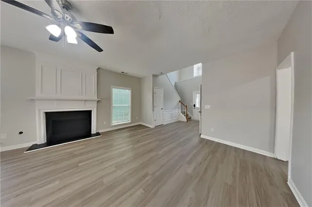 a view of an empty room with wooden floor fireplace and a window