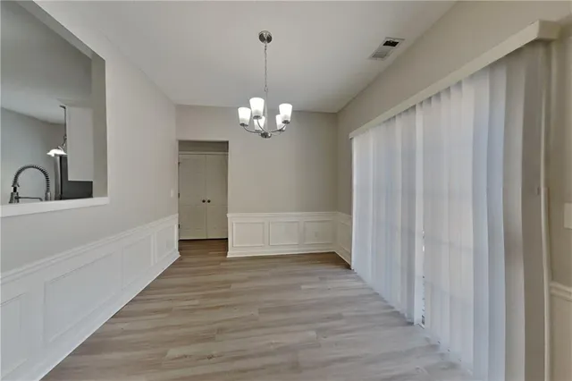 a view of a chandelier in hallway with wooden floor and chandelier