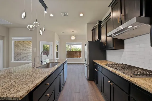 a kitchen with stainless steel appliances granite countertop sink stove and refrigerator